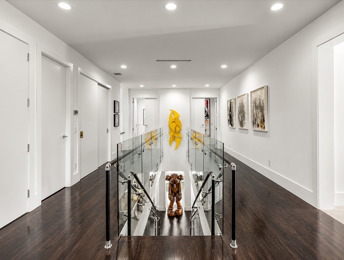 Upstairs landing with glass railing and curated art